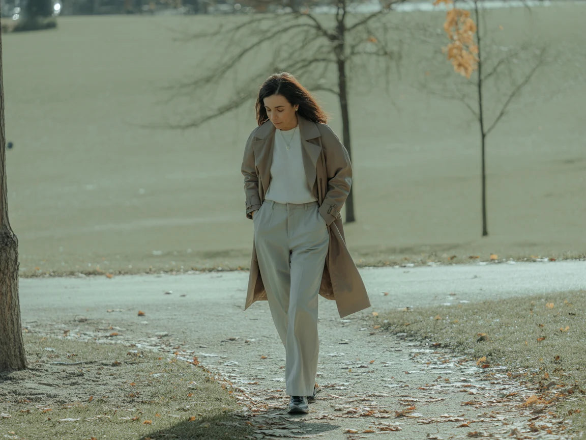 Woman walking in a park with bare trees and a light snowfall.