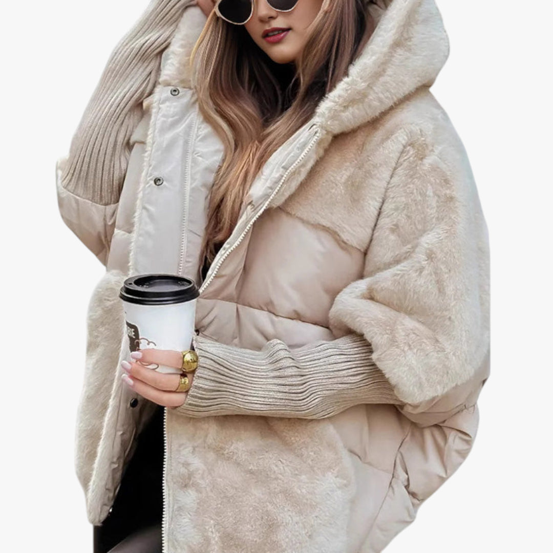 Person wearing a beige puffer jacket holding a coffee cup on a white background