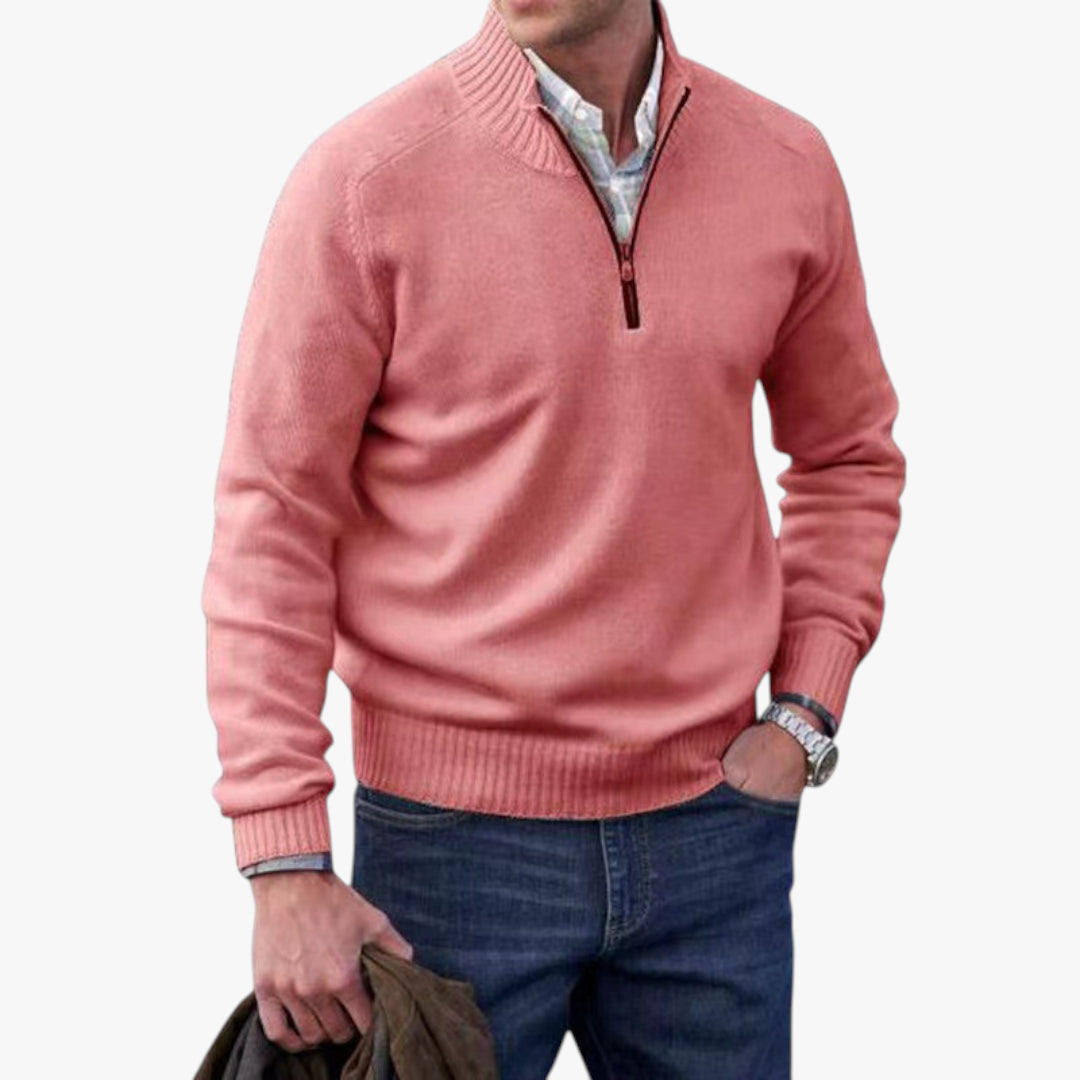 Man wearing a pink sweater with a white shirt underneath on a light gray background