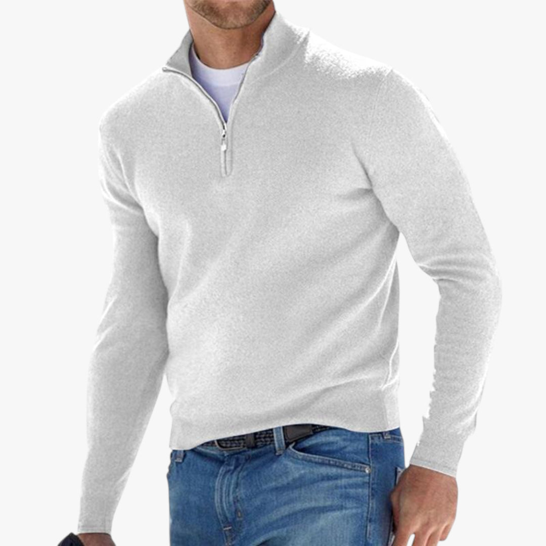 Man wearing a gray quarter-zip sweater and blue jeans on a white background