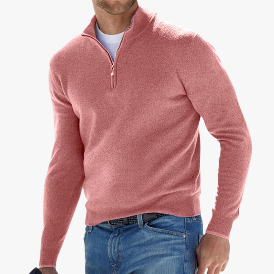 Man wearing a pink half-zip sweater and blue jeans on a white background