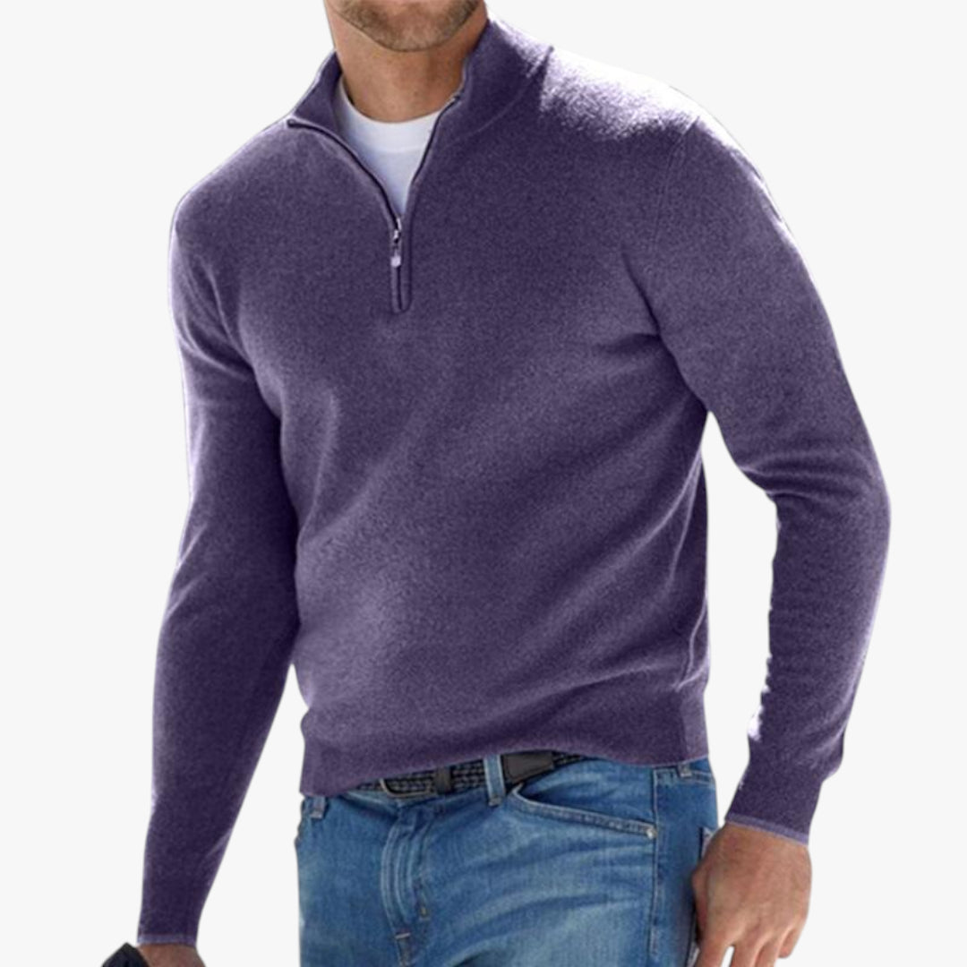 Man wearing a purple quarter-zip sweater and blue jeans on a white background