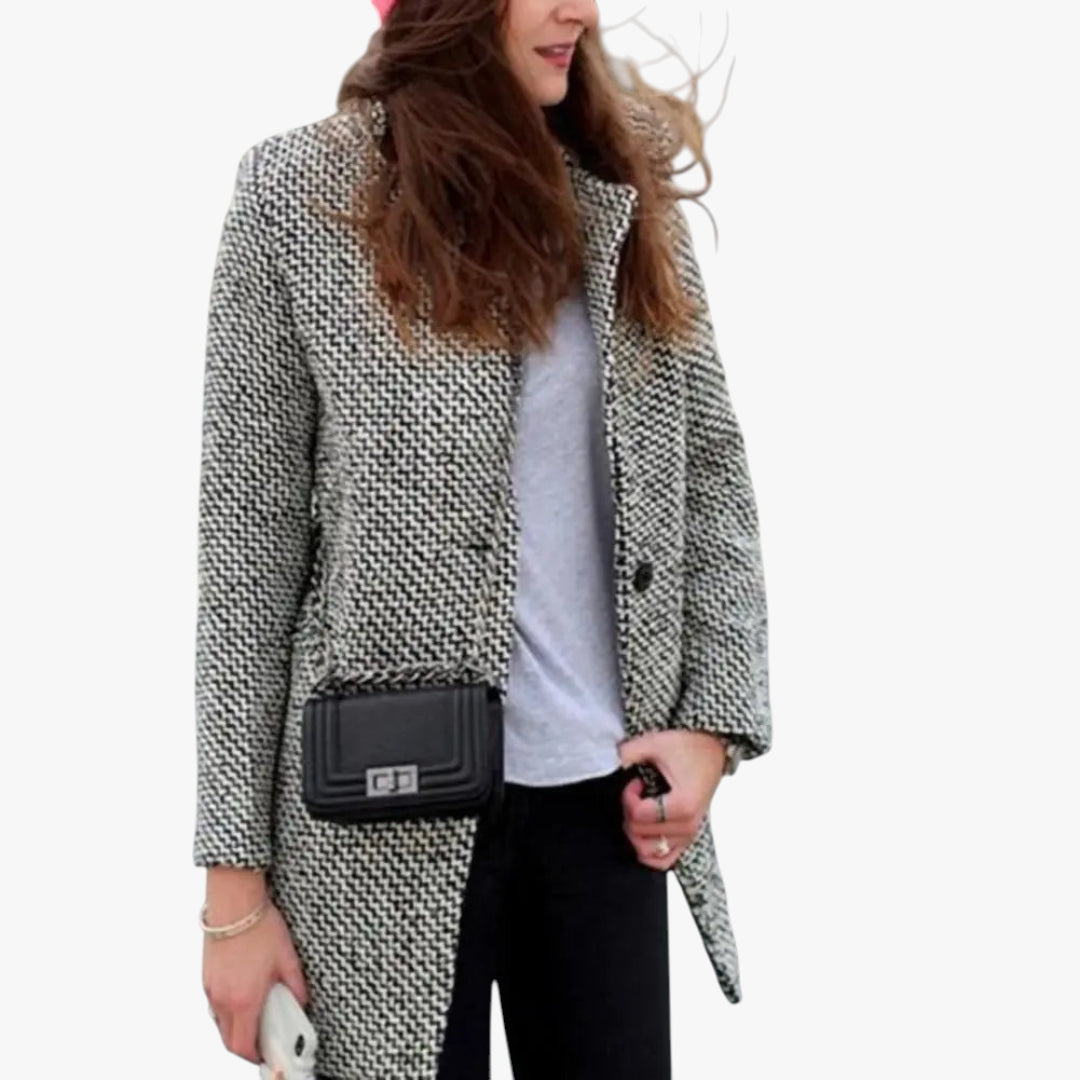 Person wearing a patterned coat with a black handbag on a white background